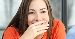 Young woman covering her smile with her hand