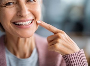 Happy senior woman pointing at her dentures