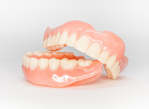 Upper and lower dentures arranged against neutral background