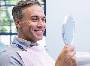 Adult patient smiling and looking at hand mirror