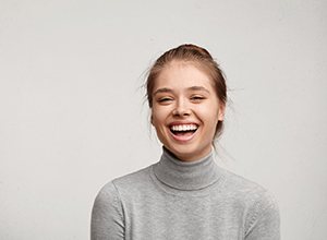 Smiling woman in gray sweater with healthy teeth