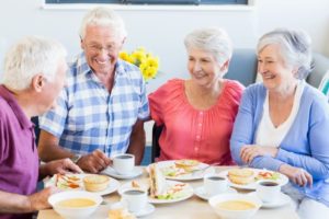 Senior friends eating a meal, thinking about dentures and taste in Abington