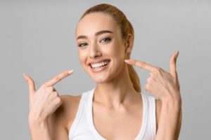 Woman pointing at her smile, showing her veneers