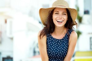 Smiling woman standing outside, wearing sunhat