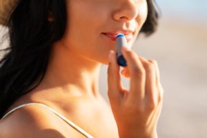 Woman standing outside, applying lip balm