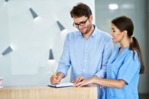 Patient and dental team member standing at dental office front desk