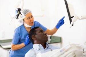 Dentist and patient looking at computer monitor, discussing treatment options