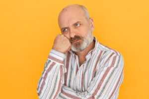 Frowning older man against yellow background 