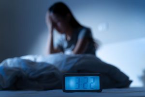 Woman with anxiety sitting up in bed